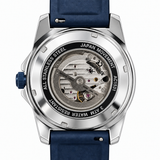 A close-up studio shot of a wristwatch showing the transparent back case and internal mechanical movement. The watch has a silver stainless steel case, a blue crown, and a dark blue strap on a white background.