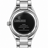 Close-up of the back of a Claudia Koch stainless steel wristwatch, showing the brushed metal case and link bracelet with a black circular insert displaying model and technical details.