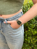 Person wearing a gold watch with a green background