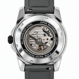 A close-up studio shot of a wristwatch back case with a transparent dial view, showing the silver stainless steel case, black strap, and visible mechanical movement inside. Text on the back ring reads 'STAINLESS STEEL', 'JAPAN MOVEMENT', '3 ATM WATER RESISTANT', and the brand name appears to be 'Swatch'.