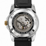 A close-up shot of a wristwatch showing its transparent back case with a visible mechanical movement. The watch has a silver stainless steel case, a black leather strap, and a gold crown, with the brand name 'Kings of Time' visible on the inner dial.